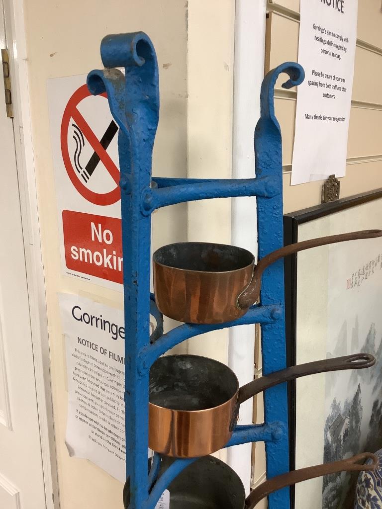 A graduating set of Victorian tin-lined copper saucepans (batterie de cuisine) on an associated tapering painted wrought iron stand